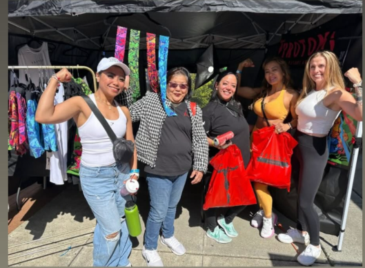 Vendors interacting with attendees at a busy booth during the Washington State Fitness Expo, showcasing fitness apparel and engaging with customers